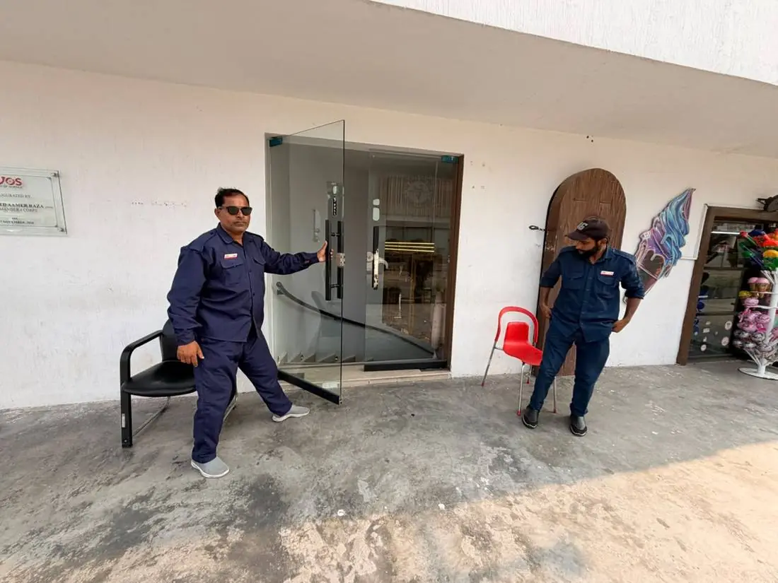 A member of staff opening the glass entrance door at Joy of Science Lahore